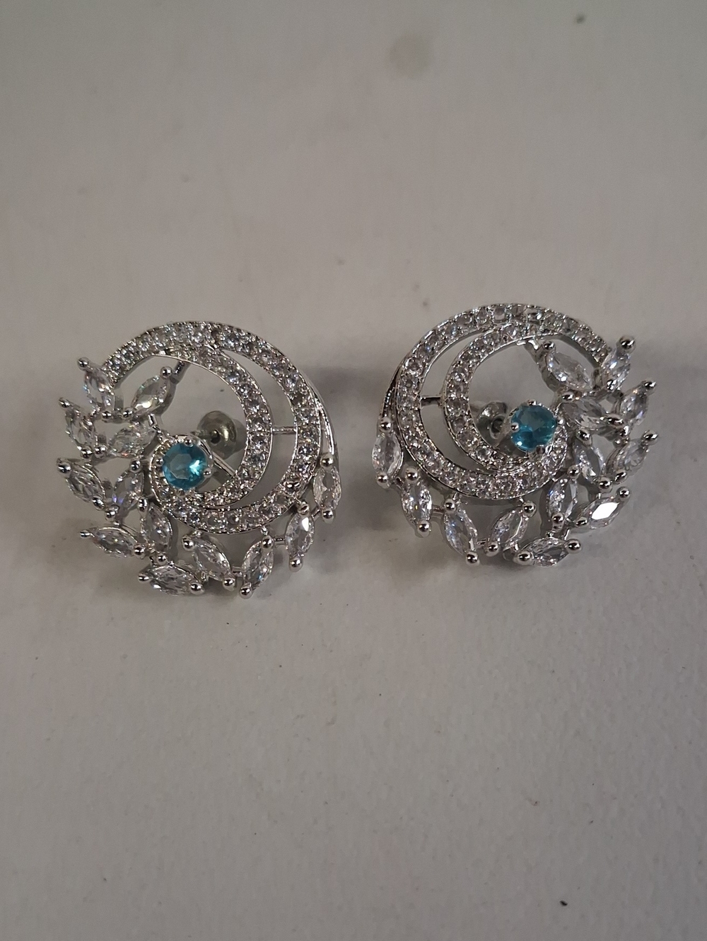 Silver Crystal Swirl Stud Earrings with Blue Center Stone